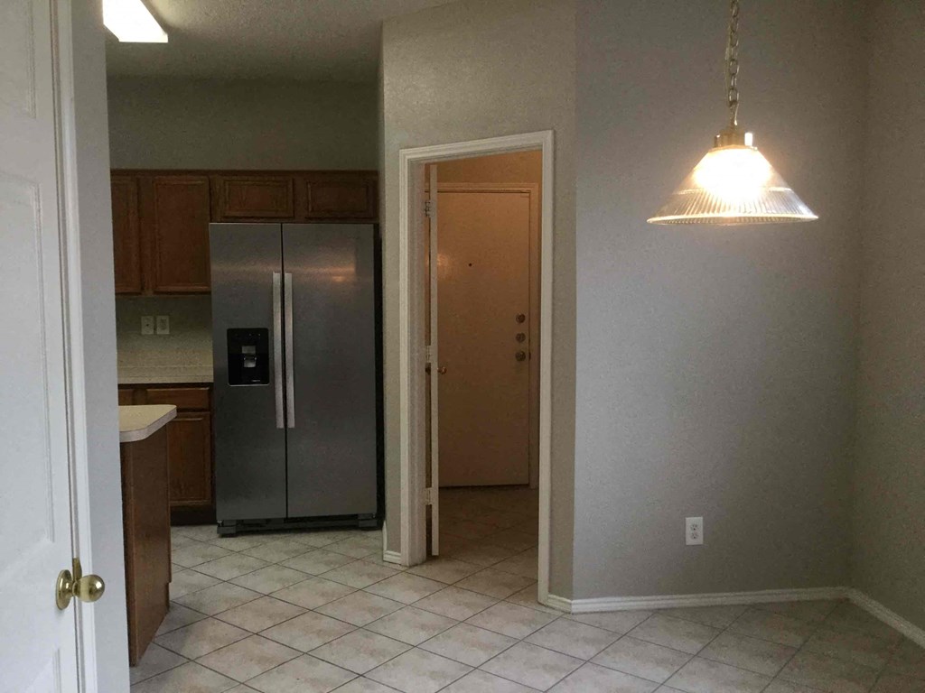 an empty kitchen with a stainless steel refrigerator  and a light