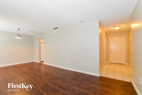 A spacious room with wooden flooring and a white door.