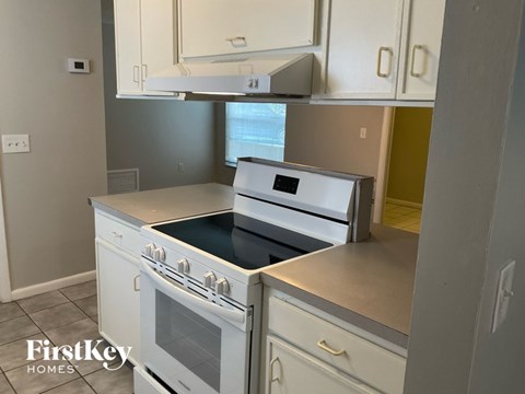 A white stove top oven with a black glass top is in a kitchen.