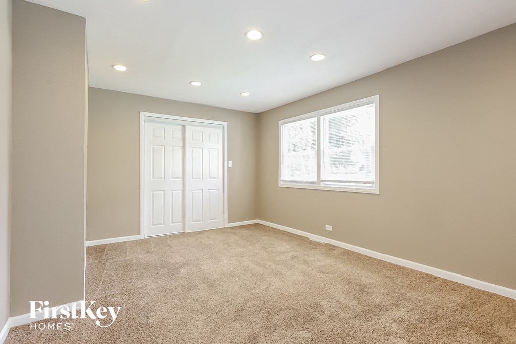 the master bedroom has a carpeted floor and a white door and window