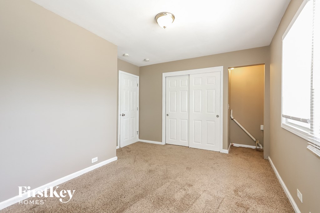 a bedroom with two closets and a carpeted floor and a staircase