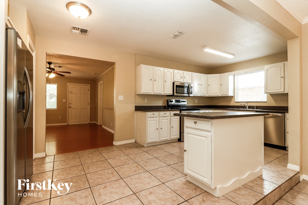 A kitchen with a refrigerator on the left and a sink in the middle.