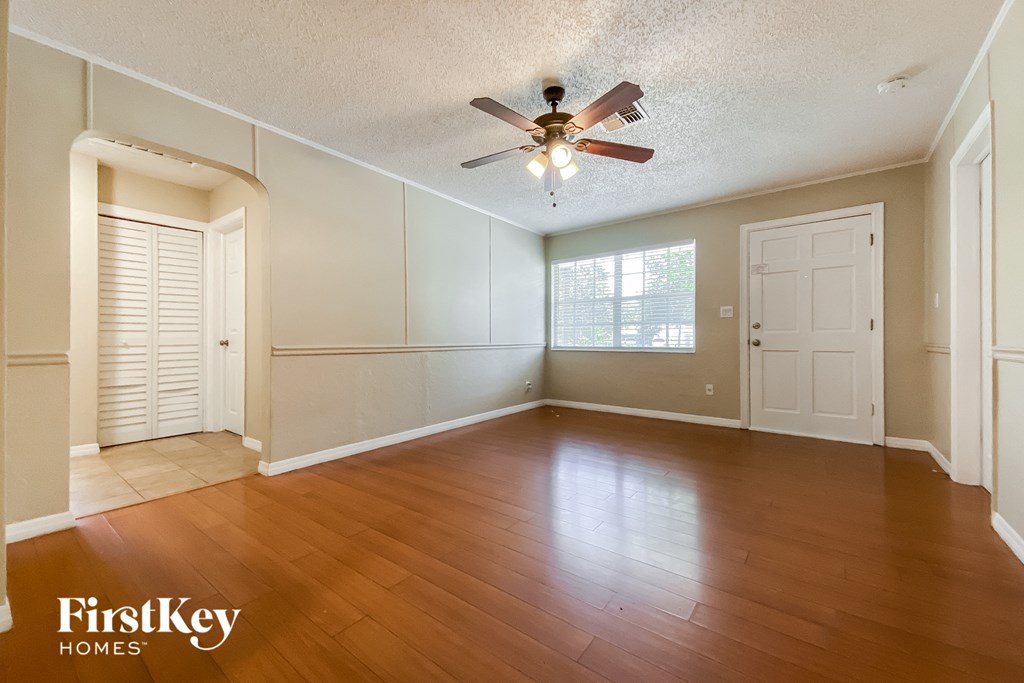 A spacious room with wooden floors and a ceiling fan.