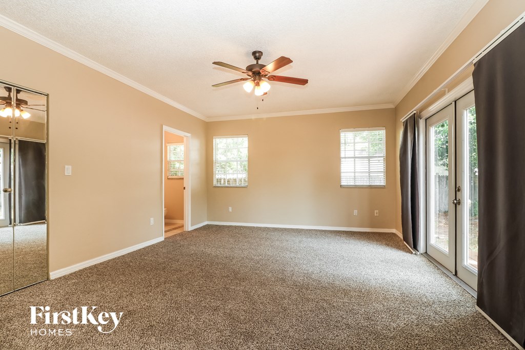 A spacious room with a ceiling fan and carpeted floor.