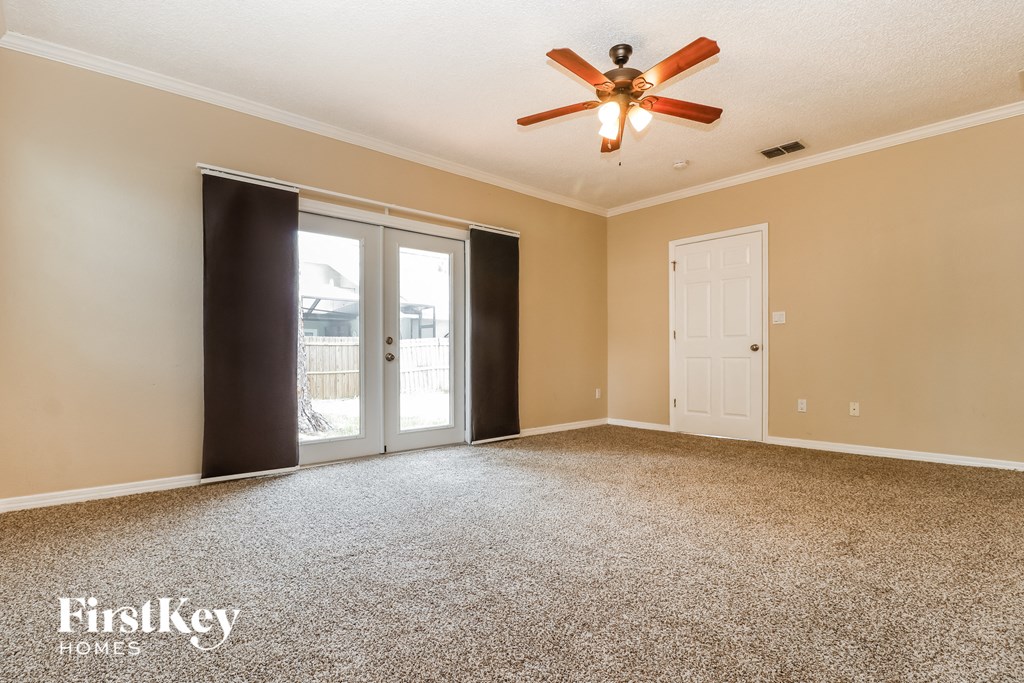 A spacious room with a ceiling fan and a carpeted floor.