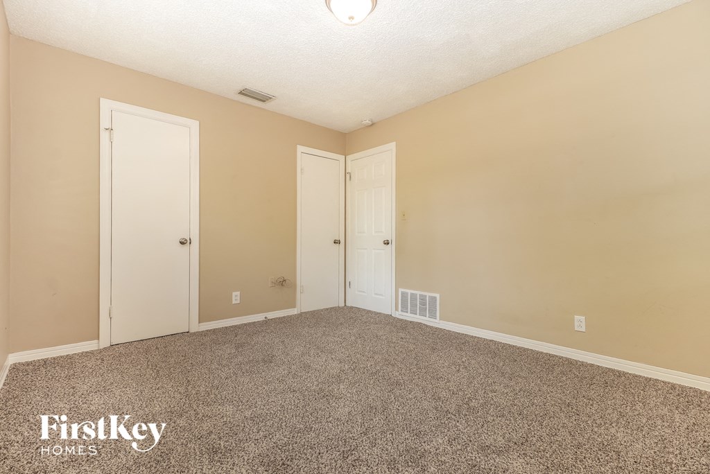 A carpeted room with two doors and a FirstKey Homes logo.