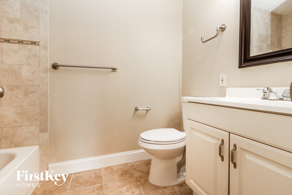 A bathroom with a toilet, sink, and a mirror.