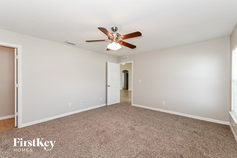 a spacious living room with carpet and a ceiling fan