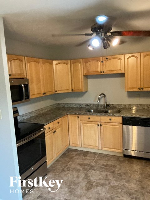 A kitchen with wooden cabinets and a stainless steel dishwasher.