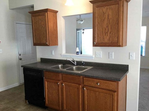 A kitchen with wooden cabinets and a black dishwasher.