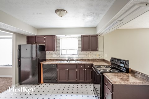A kitchen with brown cabinets and a black refrigerator.