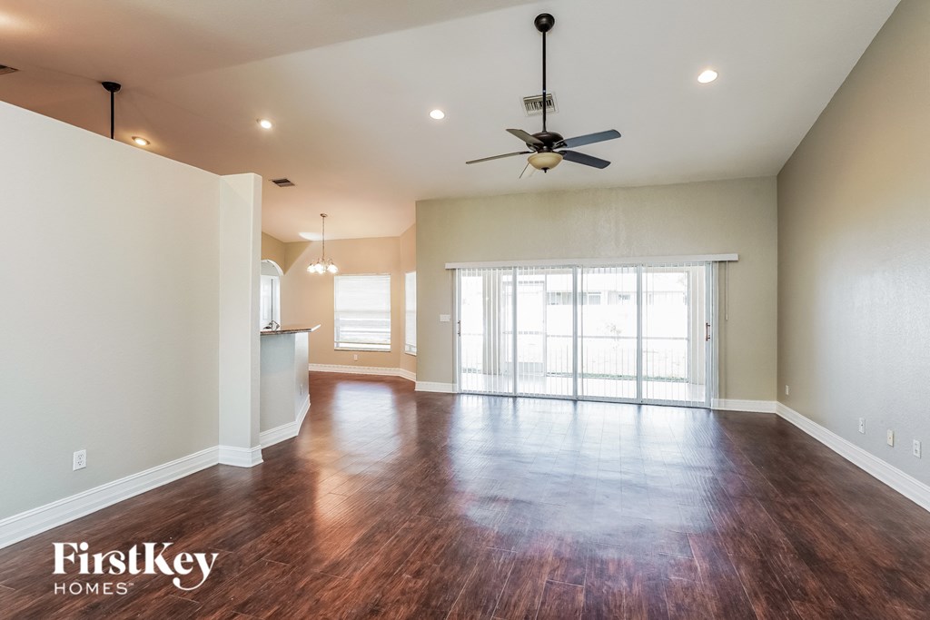 an empty living room with wood floors and a ceiling fan
