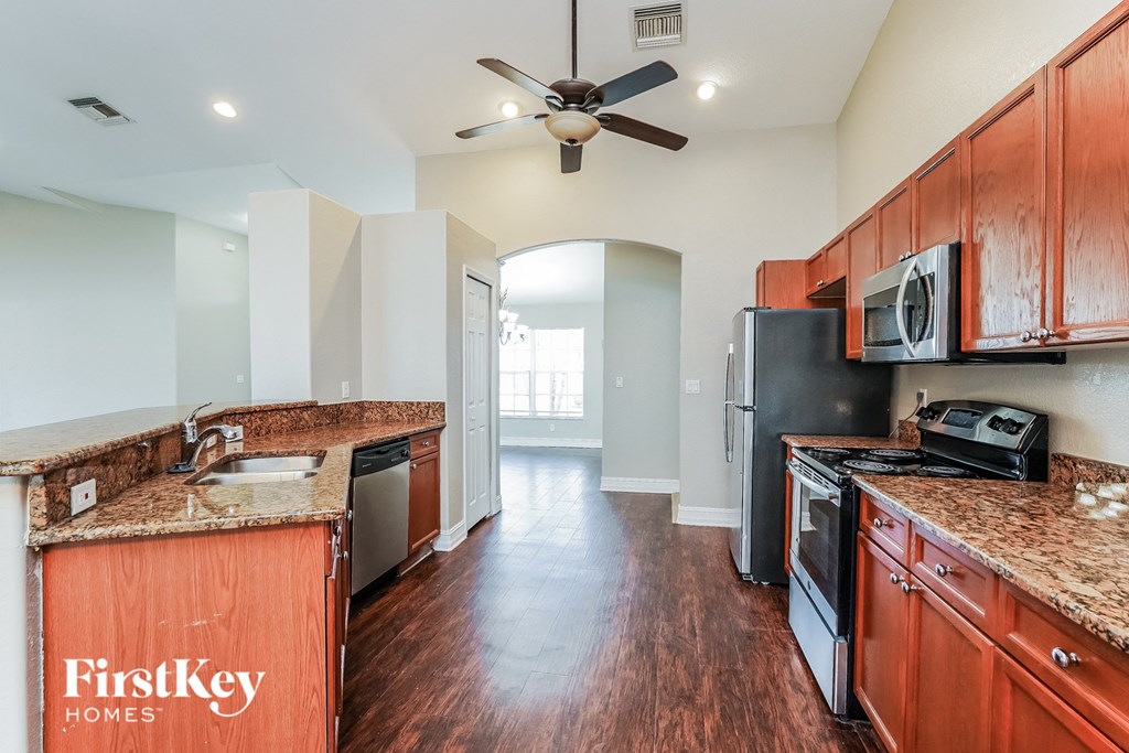 a kitchen with wooden cabinets and black appliances and a ceiling fan