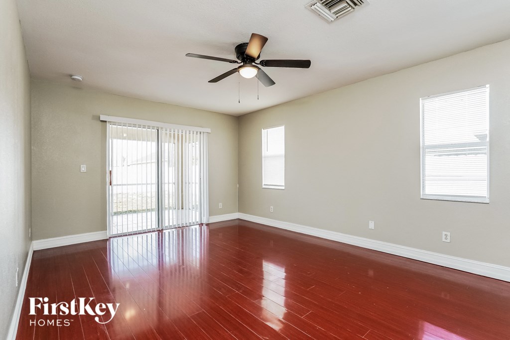 an empty living room with wood floors and a ceiling fan