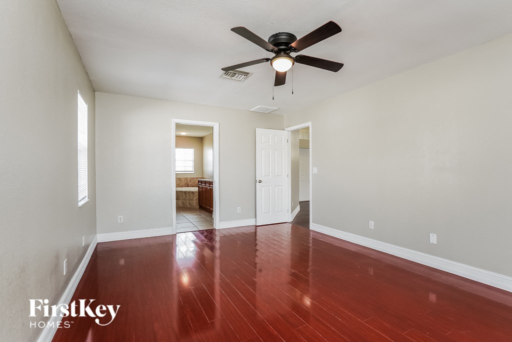 a empty living room with wood floors and a ceiling fan
