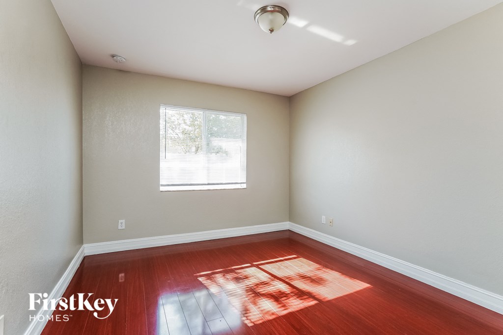 an empty room with wood floors and a window