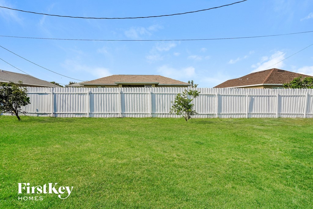 the backyard of a house with a white fence and green grass