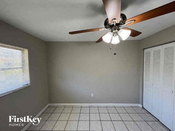 A room with a ceiling fan and a window with blinds.