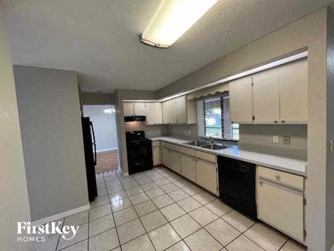A kitchen with white cabinets and black appliances.