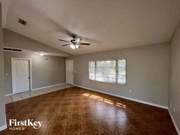 A room with a brown floor and a ceiling fan.