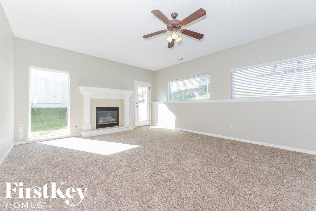 A spacious living room with a fireplace and a ceiling fan.