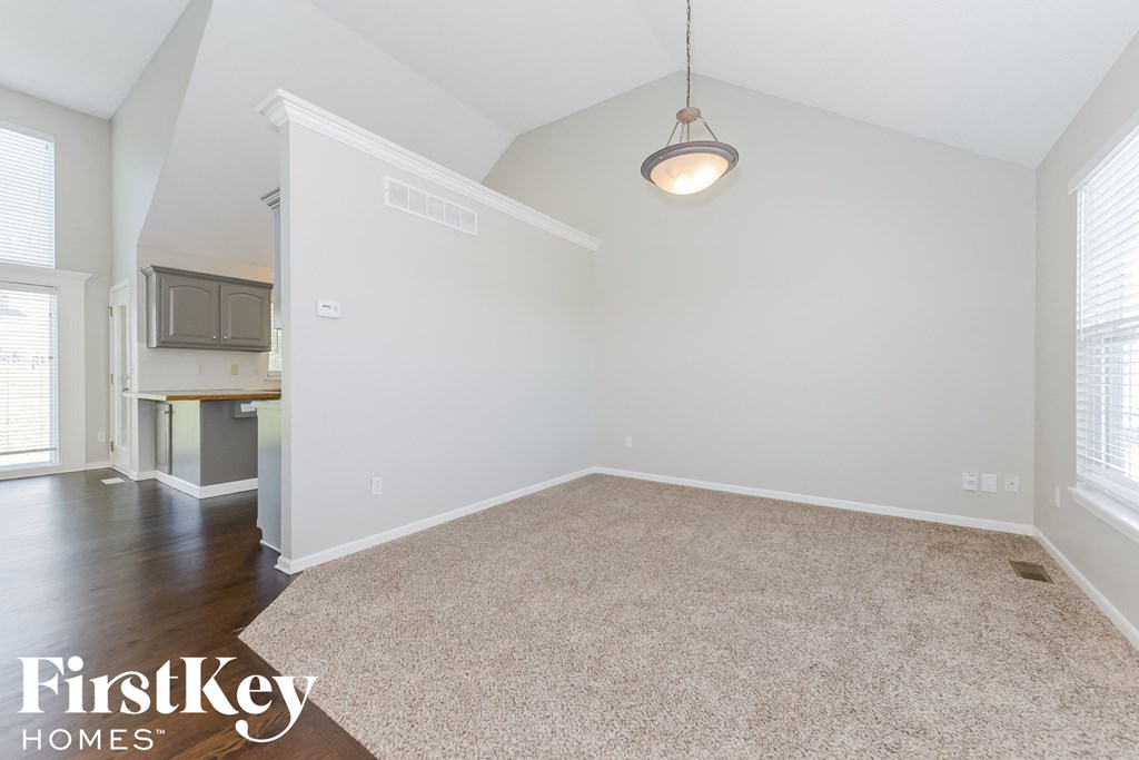 A spacious room with a carpeted floor and a hanging light fixture.