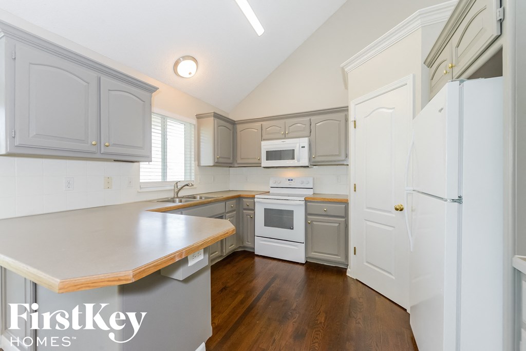 A kitchen with a white fridge and wooden countertops.