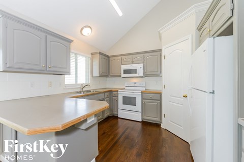 A kitchen with a white fridge and wooden countertops.