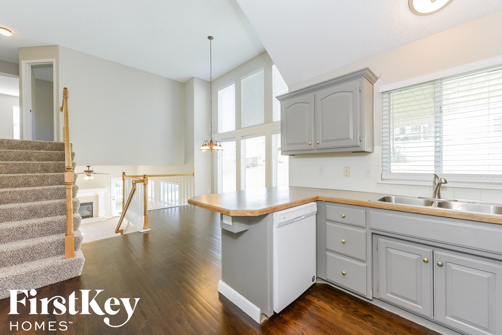A kitchen with wooden floors and a staircase.