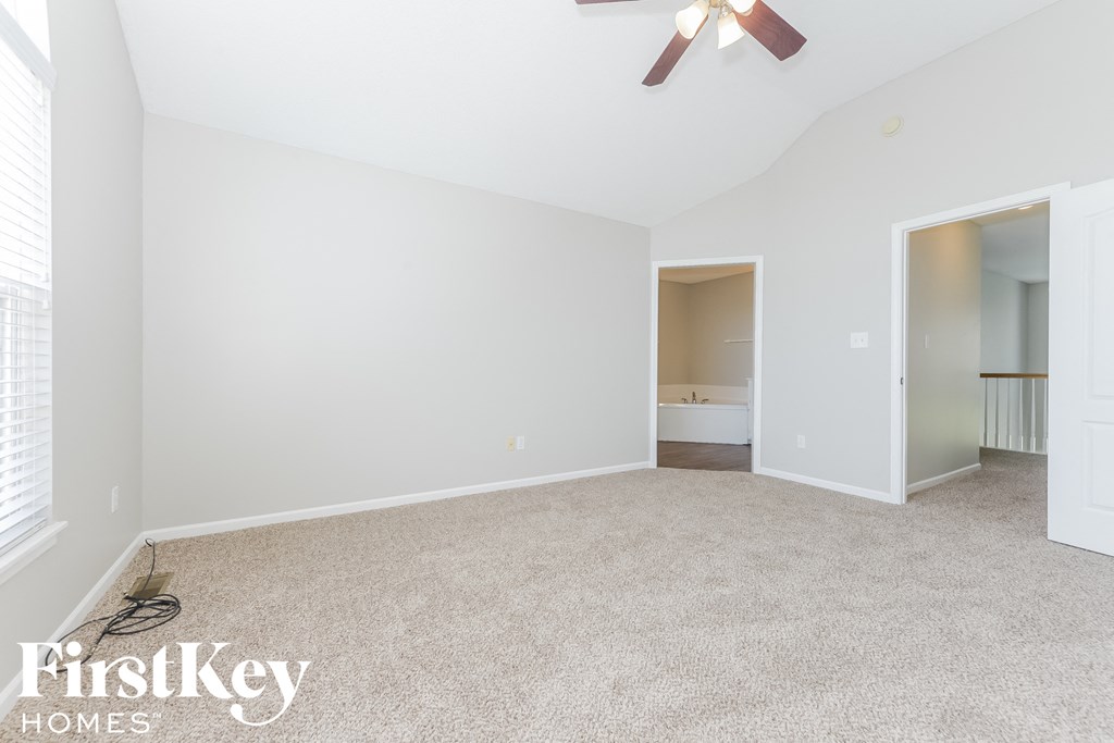 A spacious room with a ceiling fan and a window with blinds.