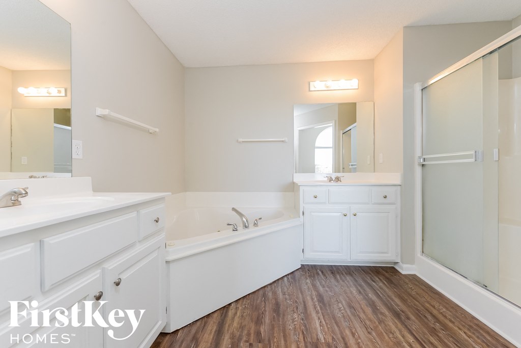 A bathroom with a tub, sink, and mirror.
