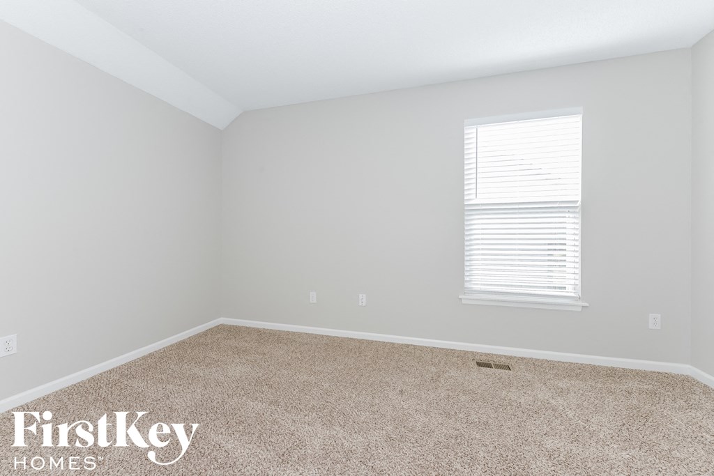 A room with a carpet floor and a window with blinds.