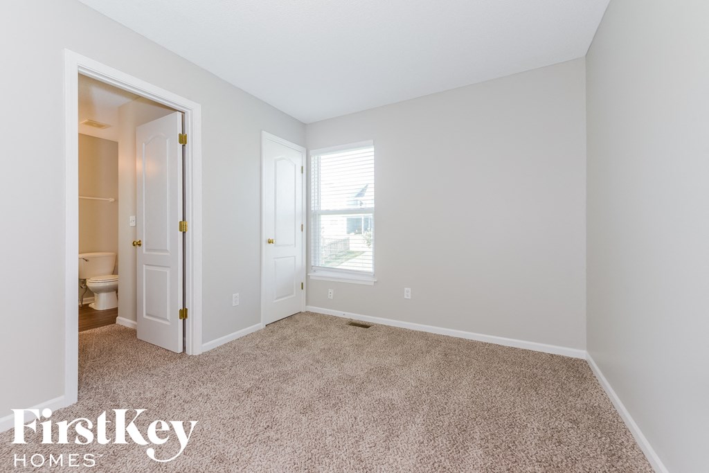 A carpeted room with a doorway leading to a bathroom.