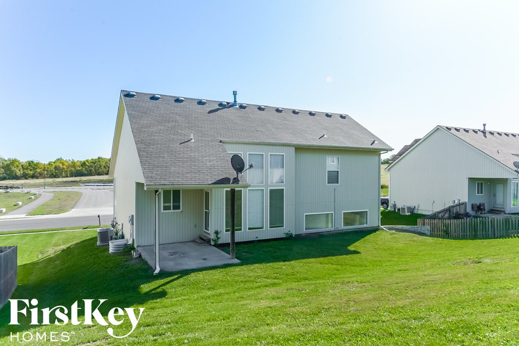 A white house with a black roof and a sign that says "FirstKey Homes".