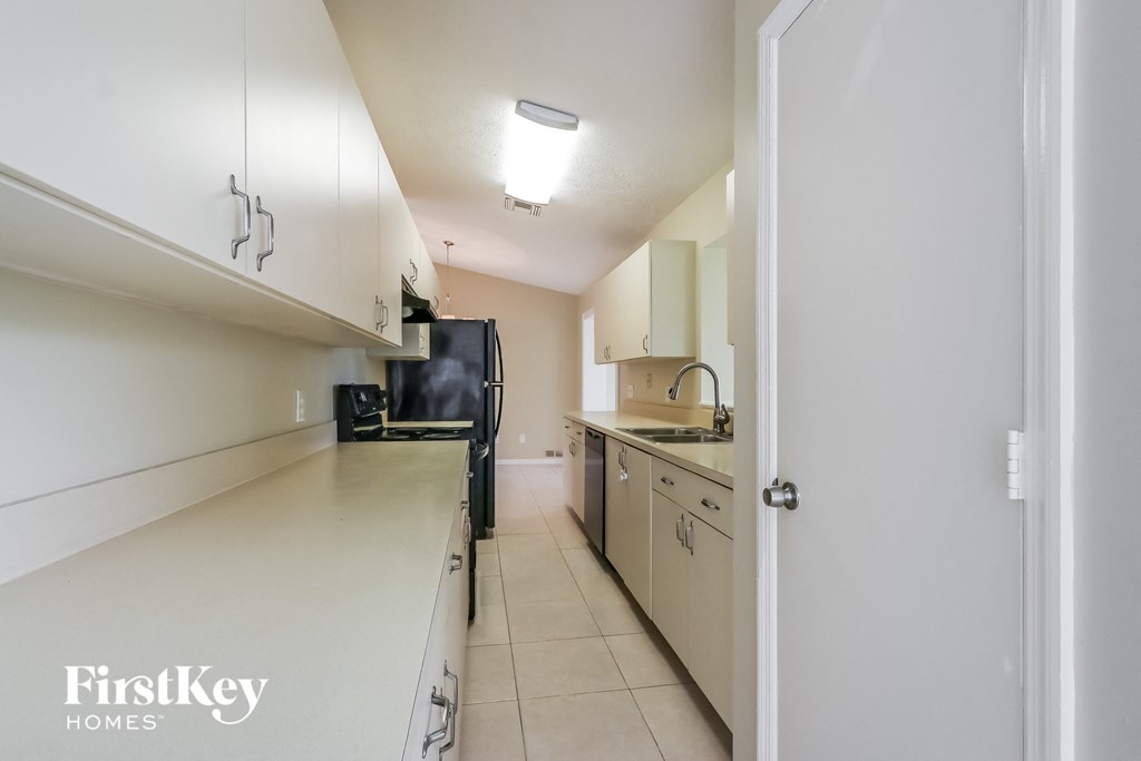 A kitchen with white cabinets and a black fridge.