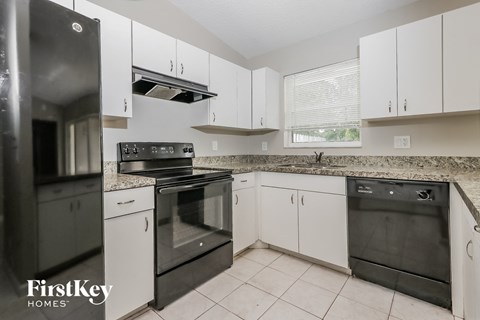 A kitchen with white cabinets and black appliances.