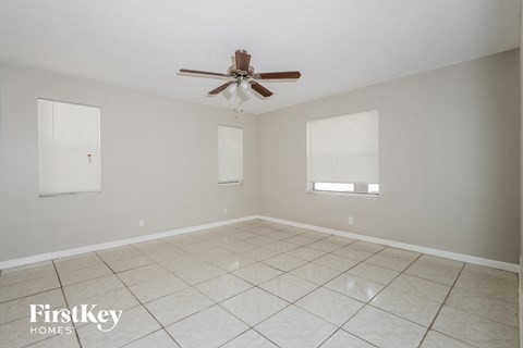 A spacious room with a ceiling fan and two windows.