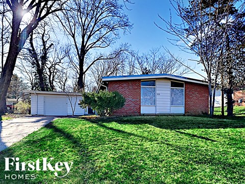 the front of a brick house with a yard and a garage