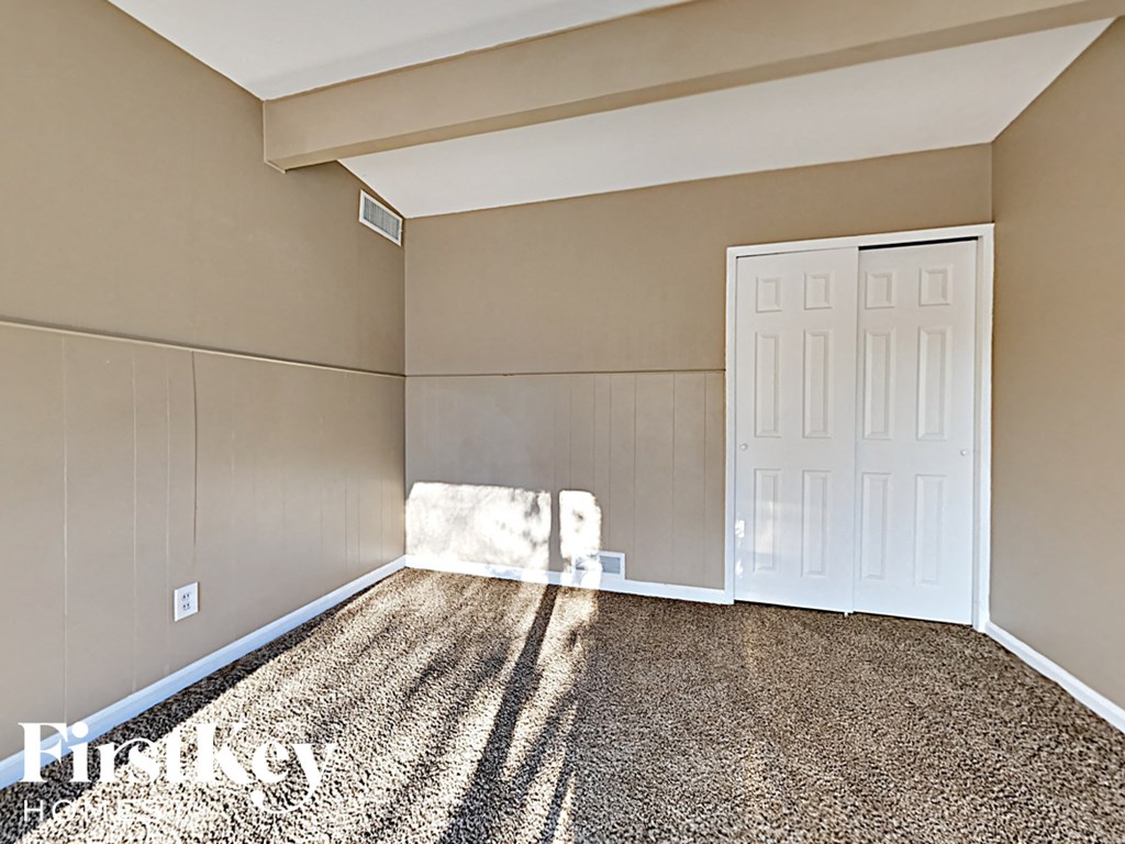 a bedroom with a white door and a carpeted floor
