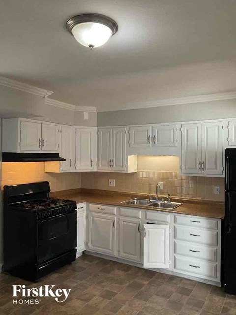 A kitchen with white cabinets and a black stove top oven.
