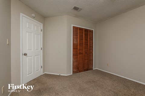 a bedroom with carpet and a door to a closet