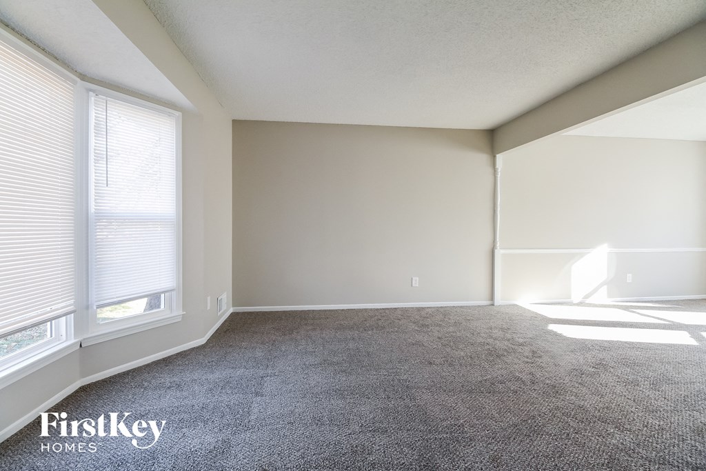 an empty living room with carpet and two windows