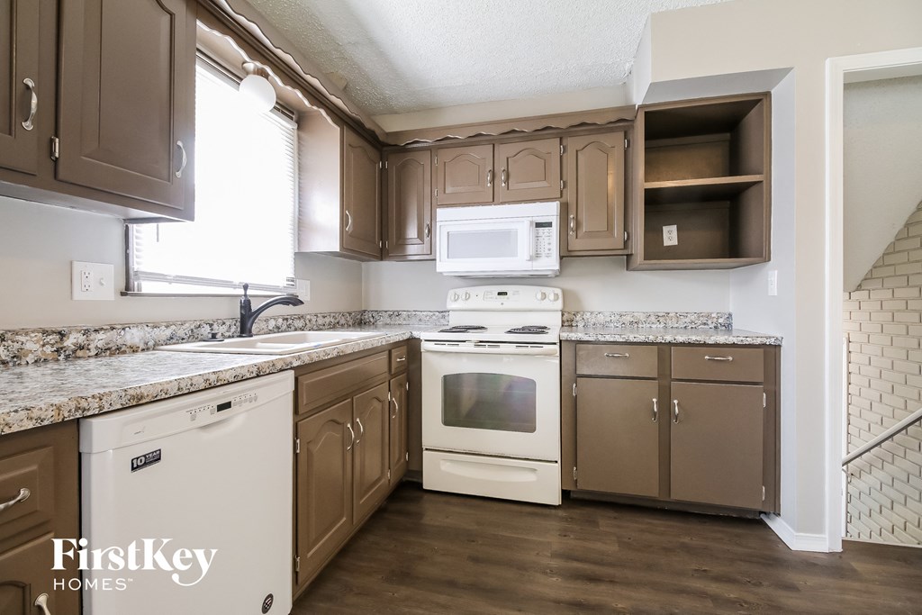 a kitchen with white appliances and brown cabinets and granite counter tops