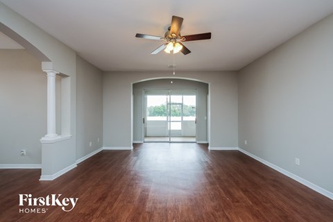 A spacious room with a ceiling fan and wooden flooring.