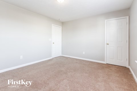 a bedroom with a carpeted floor and a white door