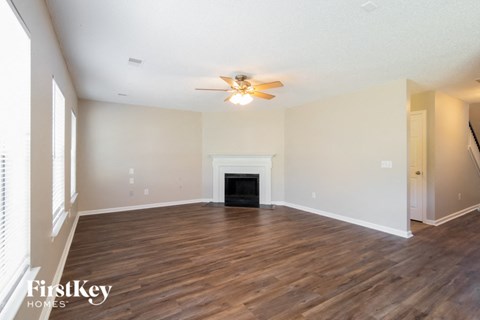 the living room with wood flooring and a ceiling fan