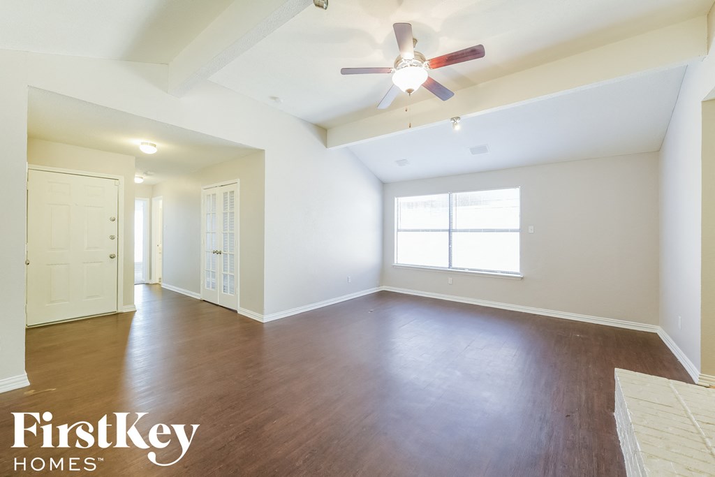 an empty living room with wood floors and a ceiling fan