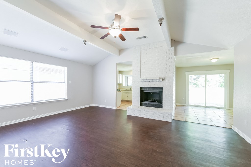 an empty living room with a fireplace and a ceiling fan