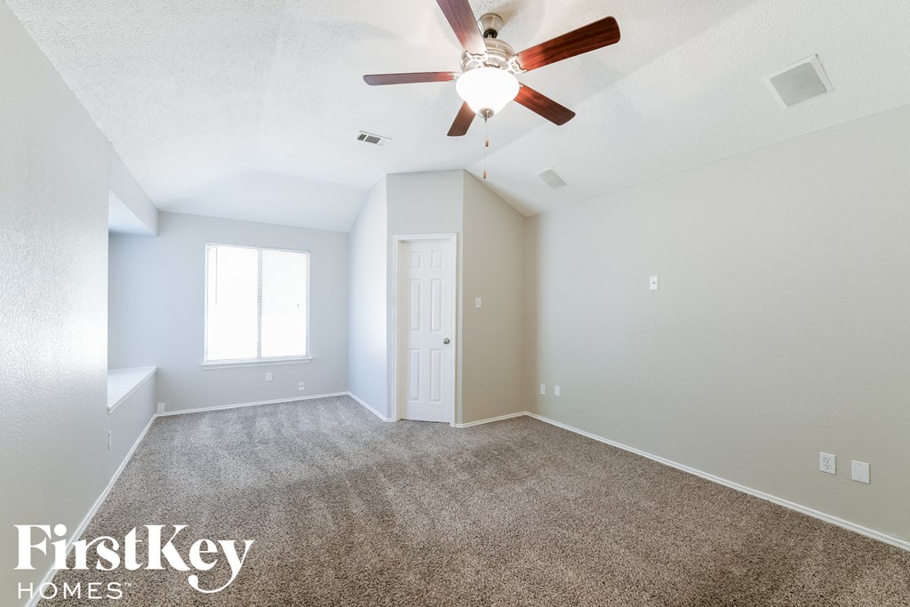 the spacious living room with ceiling fan and carpet