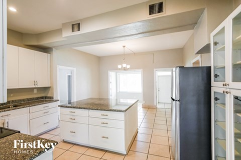 A kitchen with white cabinets and a black refrigerator.